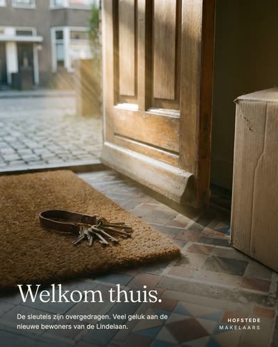 Een open voordeur met een sleutelbos op de deurmat en een verhuisdoos in de gang, met de tekst: Welkom thuis. De sleutels zijn overgedragen. Veel geluk aan de nieuwe bewoners van de Lindelaan. Hofstede Makelaars.